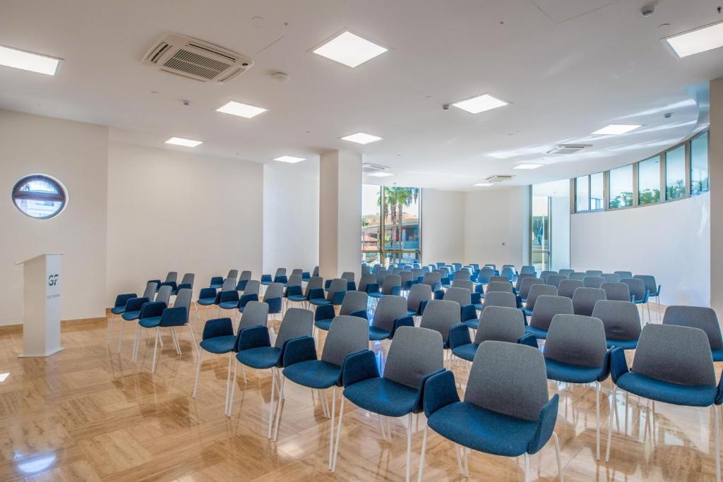 Konferenču telpa ar organizētām krēsliem un modernu dizainu, kas nodrošina gaišu un ērtu vidi. Loga izskats un dabiskā apgaismojuma klātbūtne piešķir telpai patīkamu atmosfēru.