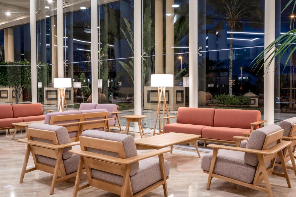 Mūsdienīgs viesnīcas atpūtas zonas interjers ar stilīgām mēbelēm, lieliem logiem un siltu apgaismojumu. Pārsvarā izmantoti koka un mīkstās mēbeles, radot mājīgu atmosfēru.