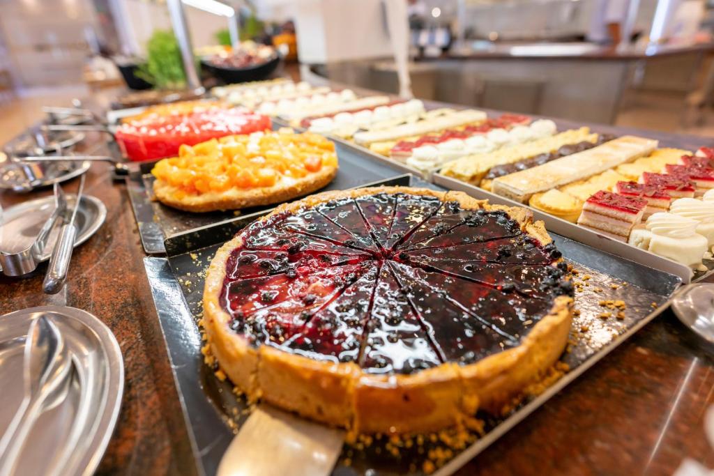 Deserta bufete ar dažādiem kūku veidiem, tostarp ogu un augļu pīrāgiem, kas izkārtoti uz galda.