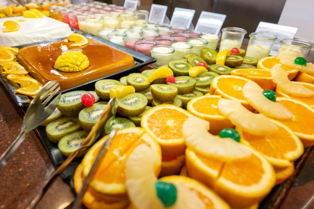 Krāsains desertu bufete ar dažādiem augļiem, tostarp apelsīniem, kivi un ananāsiem, kā arī dažādiem saldumiem. Izcils izvēles klāsts, kas pievilina ar savu vizuālo pievilcību.