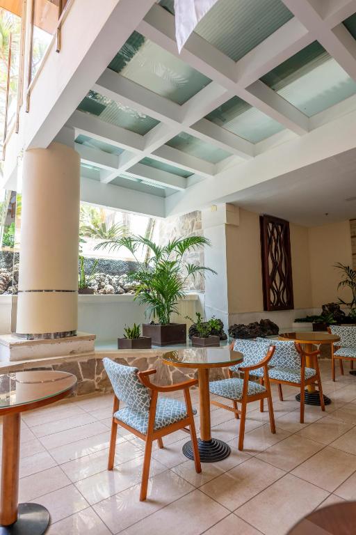 Mūsdienīgs interjers ar stilīgām krēsliem un galdiem, kas izvietoti plašā telpā ar dabīgiem elementiem un augiem. Gaismas avots ir caurspīdīgā griestu konstrukcija, kas piešķir telpai gaišumu un svaigumu.