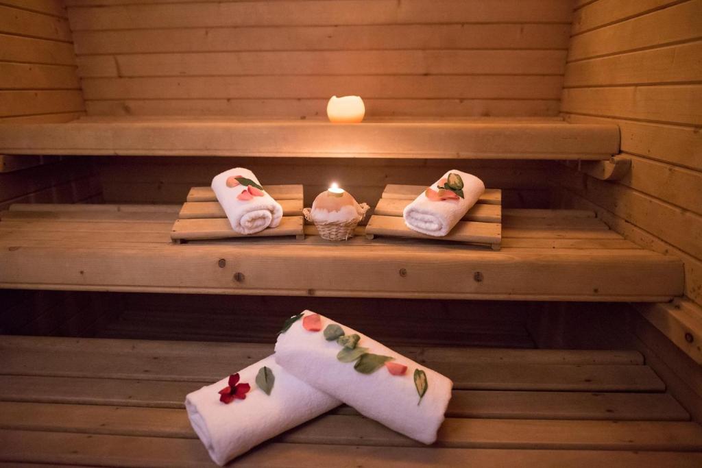 Koka pirts ar baltiem dvieļiem, kas rotāti ar ziedlapiņām, un svecēm, kas rada relaksējošu atmosfēru. Ideāla vieta atpūtai un labsajūtai.