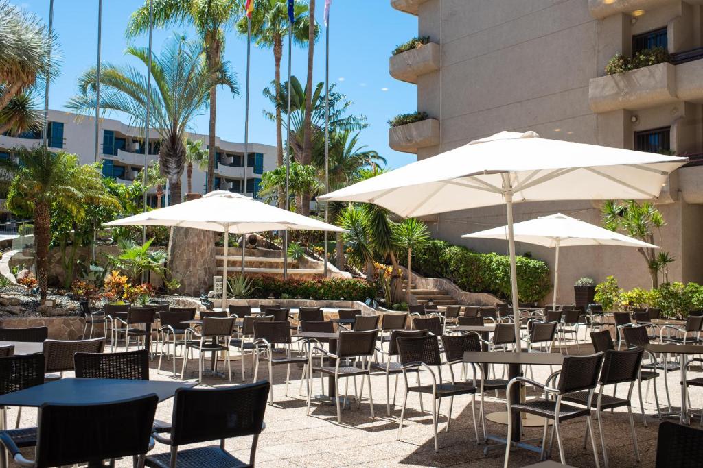 Āra terase ar saulessargiem un krēsliem, apkārt palmām un zaļumiem, radot relaksējošu atmosfēru. Ideāla vieta ģimenes vai draugu sanākumiem.