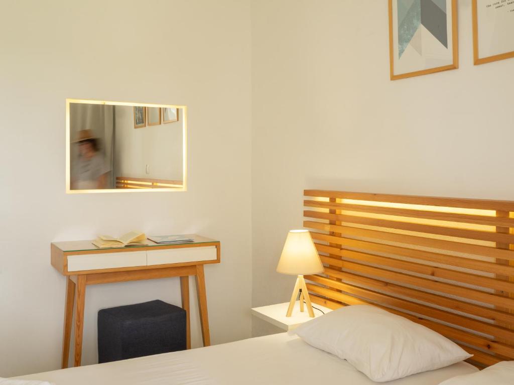 Moderna guļamistaba ar koka gultas galvgali, elegantu galdu un lampu, kā arī spoguli, kas atspoguļo telpas noskaņu. Rāmētas gleznas papildina interjeru.