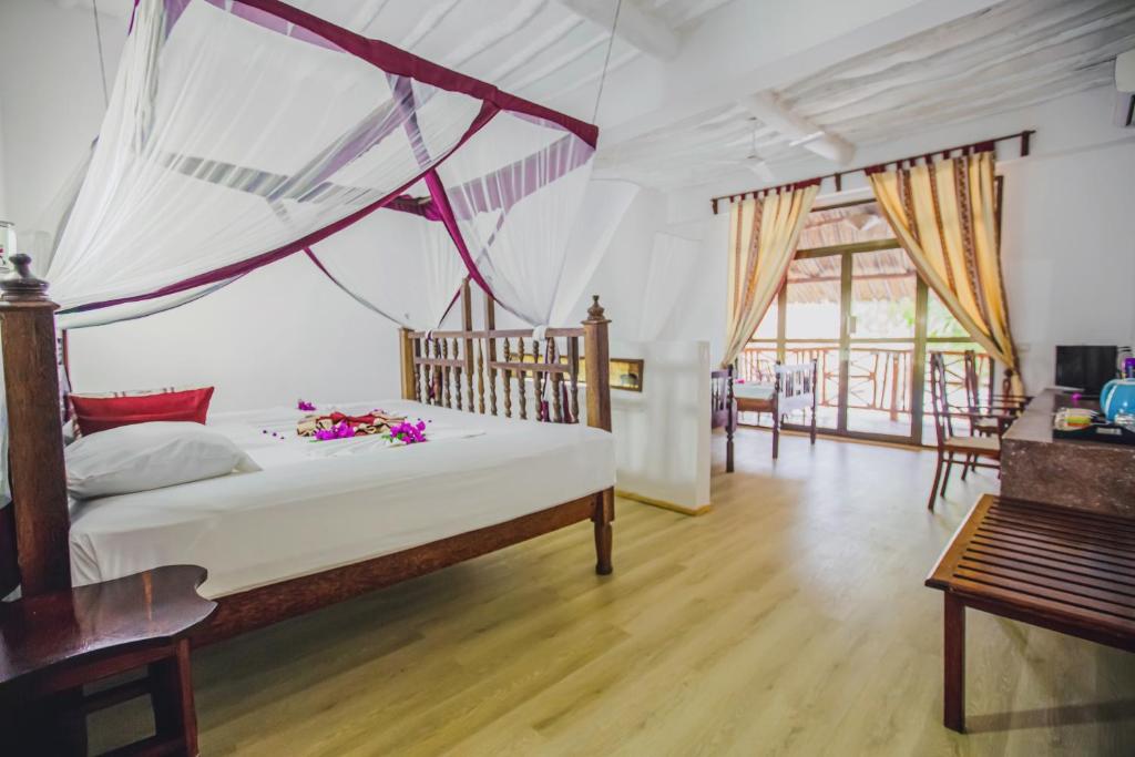 Romantisks numurs AHG Waridi Beach Resort & Spa ar balkonu un gultu ar moskītu tīklu.