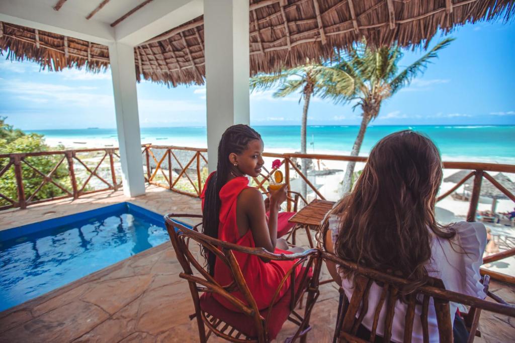 Divas viesi izbauda dzērienus terasē pie AHG Waridi Beach Resort & Spa ar skatu uz jūru.