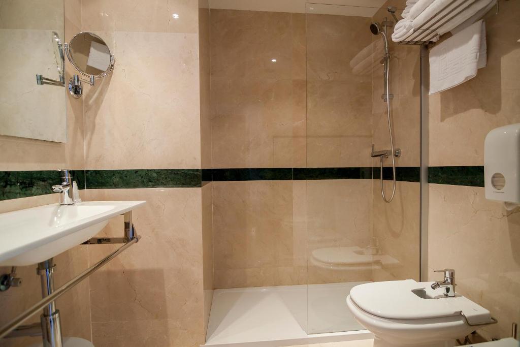 Mūsdienīga vannas istaba ar stikla dušu, pelēku akmens apdari un higiēnas piederumiem. Eleganta un funkcionāla telpa.