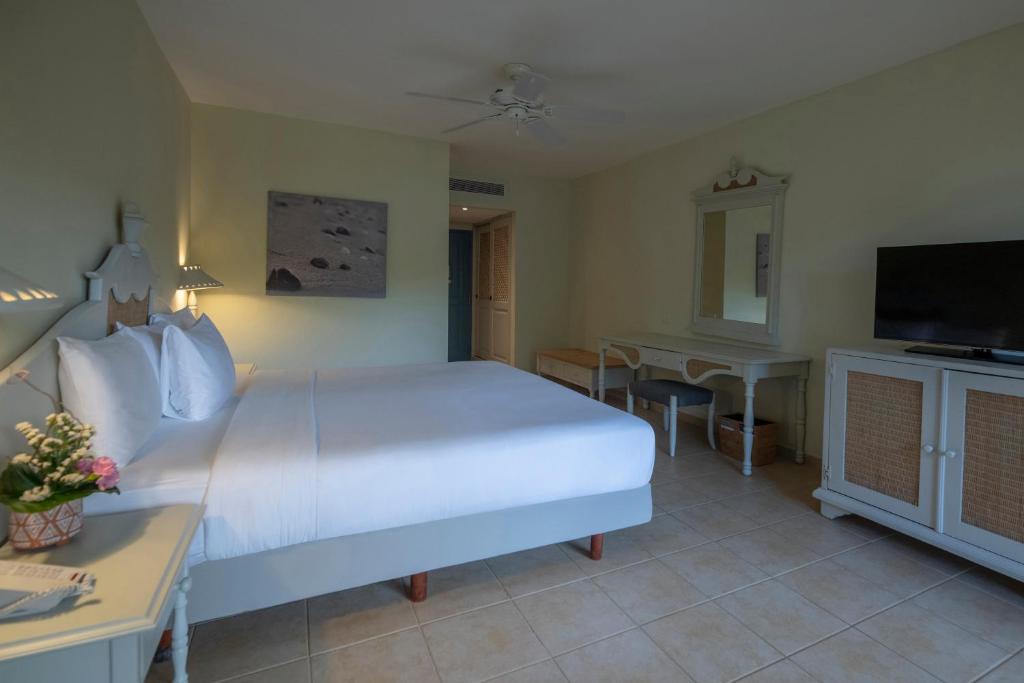 Mūsdienīga viesnīcas numura interjers ar plašu gultu, gaismu un elegantām mēbelēm. Numurā ir televizors, spogulis un dekoratīvie elementi, kas rada mājīgu atmosfēru.