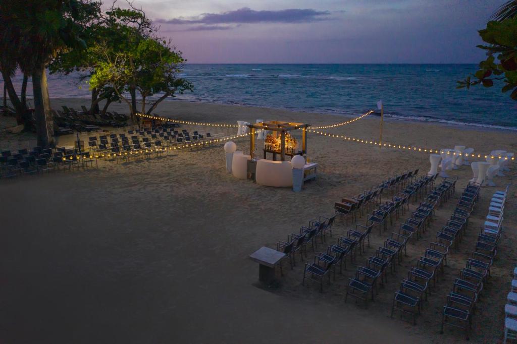 Pludmales kāzas ar sēdvietām un gaismas virtenēm, kas izgaismo ceremonijas vietu. Skaista ainava pie jūras vēlā vakarā.