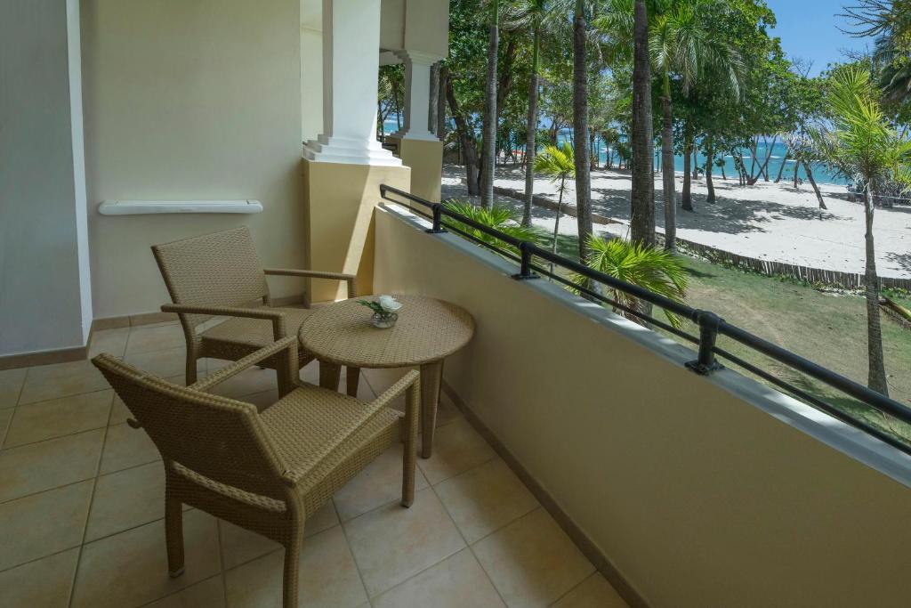 Balkons ar divām krēslām un galdu, no kura paveras skats uz pludmali un palmām. Ideāla vieta relaksācijai un atpūtai.