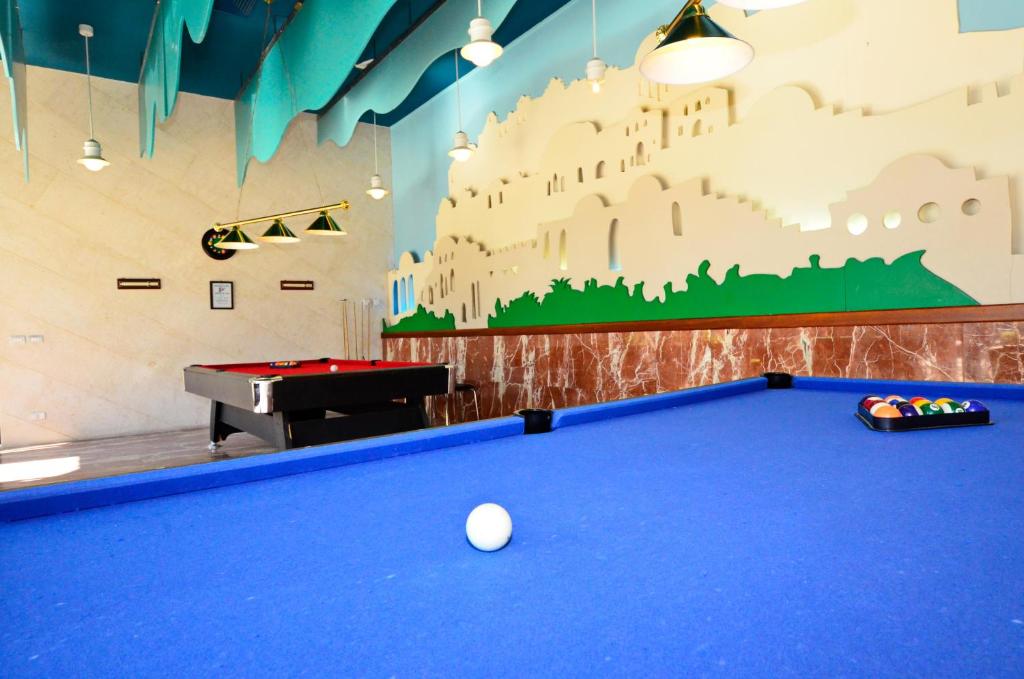 Billiards telpa ar zilu galdu un sarkanu biljarda galdu, dekorēta ar spilgtu sienas gleznojumu.