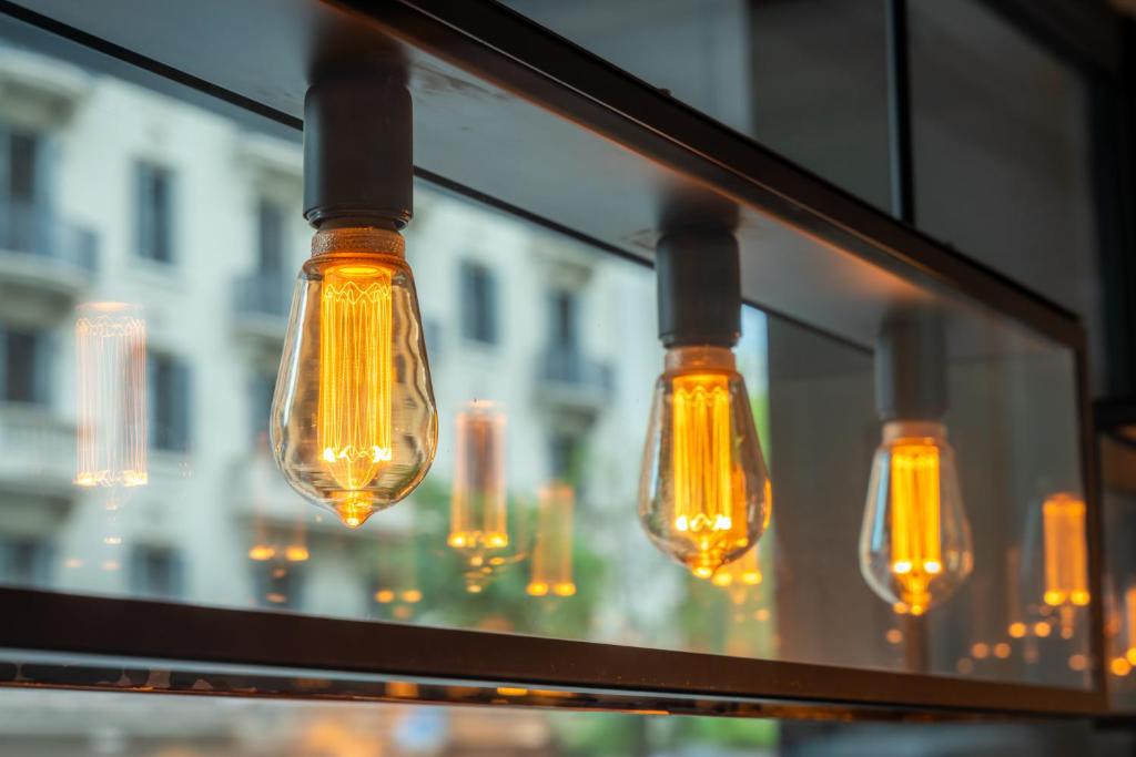 Stilīgas vintage lampas ar siltu gaismu, kas atspoguļojas logā, radot mājīgu atmosfēru.