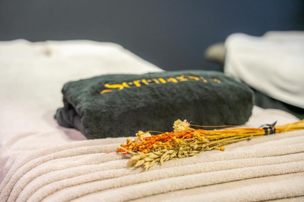 Mīksts dvielis un žāvēti ziedi, kas novietoti uz masāžas galda, radot relaksējošu atmosfēru. Ideāli piemērots spa un labsajūtas apkārtnei.