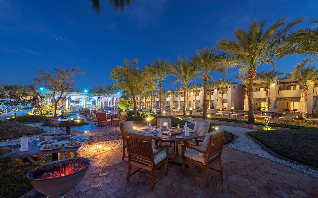 Kafejnīca pie Sentido Reef Oasis Senses Resort ar palmām un mīkstu apgaismojumu