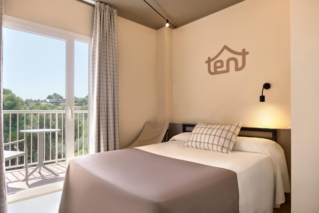 Gaiša guļamistaba ar balkonu, kurā ir divguļamā gulta un raksturīgs dekors. Logā redzams skats uz dabu, radot mierīgu atmosfēru.