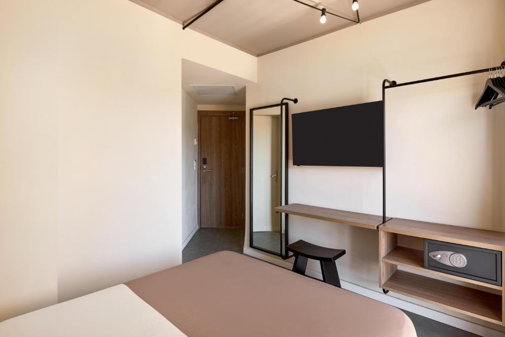 Mūsdienīga viesnīcas numura interjers ar gultu, skapi, televizoru un koka galdu. Gaismas un neitrālas krāsas rada patīkamu atmosfēru.