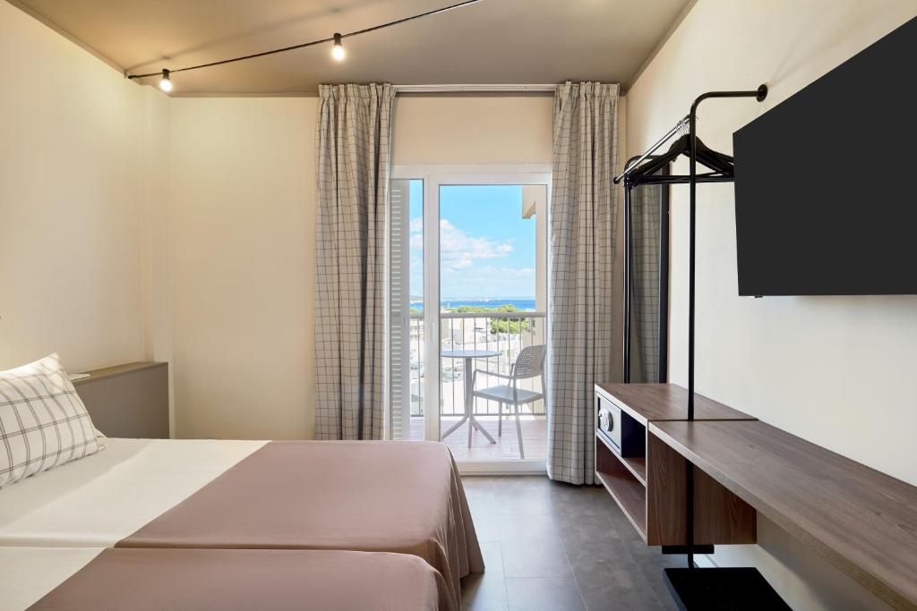 Moderns viesnīcas numurs ar balkonu un skatu uz jūru. Interjerā ir gaisīgas krāsas un minimālistisks dizains, iekļaujot televizoru un apģērbu stendu.