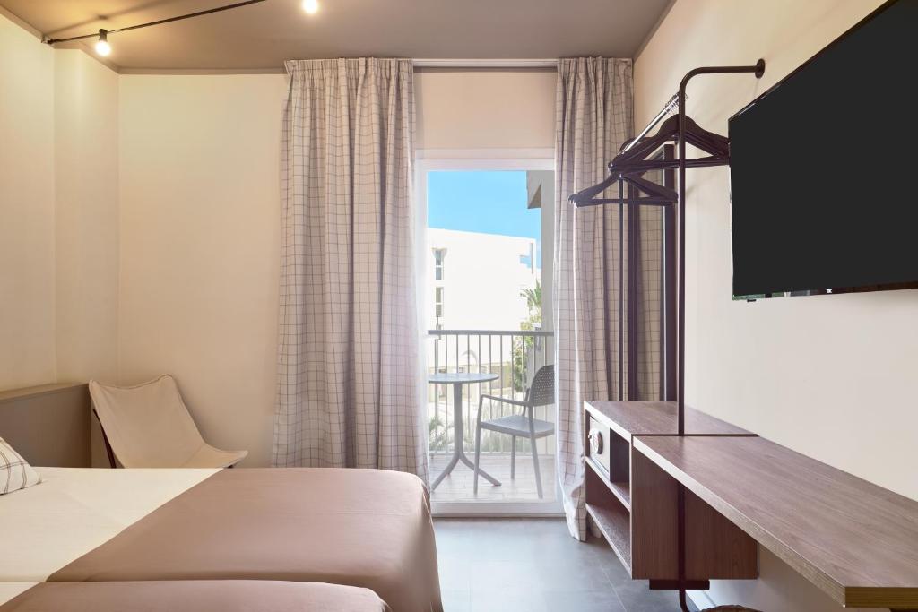 Mūsdienīga viesnīcas numura iekārtojums ar gultām, televizoru un balkonu. Logi nodrošina dabiski apgaismojumu un skatu uz ārpusi.