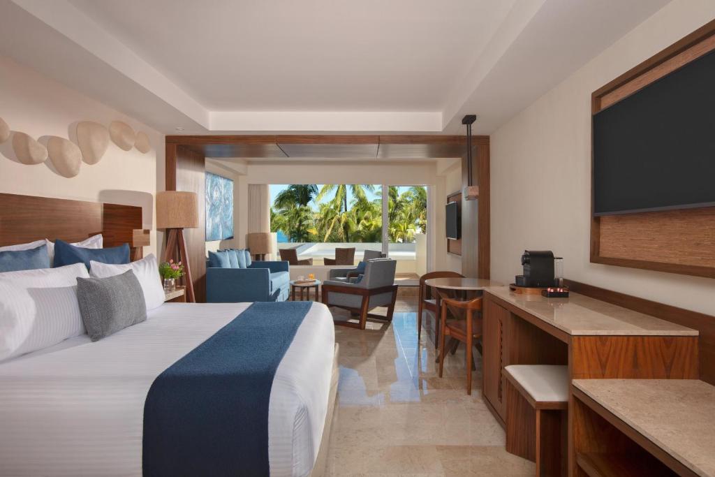 Mūsdienīgs viesnīcas numurs ar lielu logu, kas paver skatu uz palmām. Interjers ir gaišs un elegants, ar ērtu gultu un sēdvietām atpūtai.