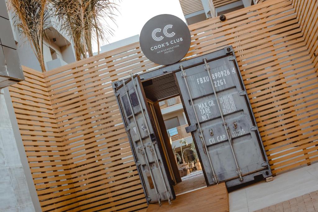 Ieeja modernā viesnīcā "Cook's Club", kas izceļas ar radošu dizainu un industrijas stilu, ar atvērtiem durvīm un koka žogu.