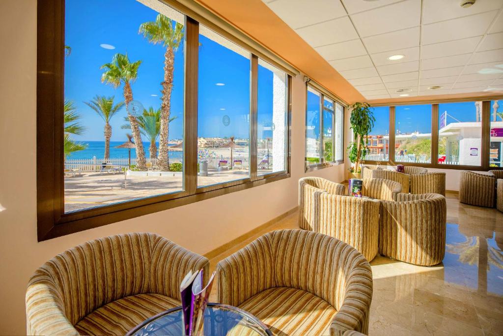 Gaiša un moderna viesnīcu uzgaidāmā telpa ar komfortablām krēslām un plašiem logiem, caur kuriem redzama pludmale un palmas. Ideāla vieta atpūtai un relaksācijai.