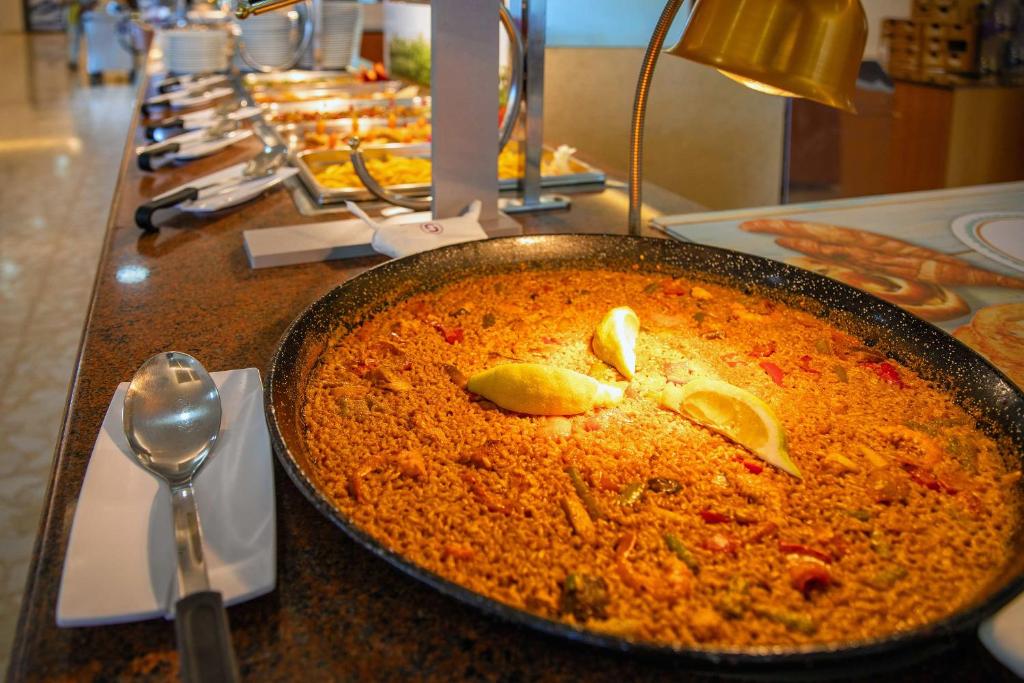 Svaigs un garšīgs paeljas ēdiens, pasniegts bufetē ar citrona šķēlītēm. Gatavots ar dārzeņiem un aromātiskām garšvielām, radot pievilcīgu vizuālo izskatu.