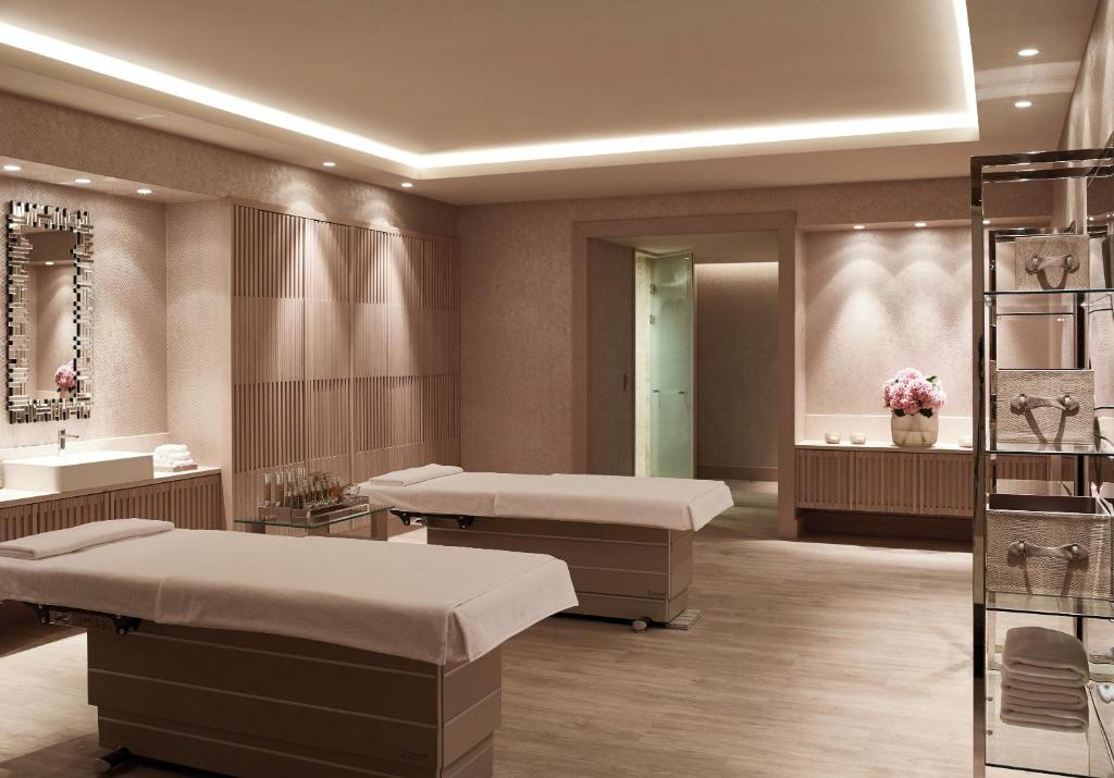 Mūsdienīgs spa interjers ar divām masāžas gultām, elegantu spoguli un relaksējošu atmosfēru. Telpā ir silti toņi un apgaismojums, kas veicina atpūtu.