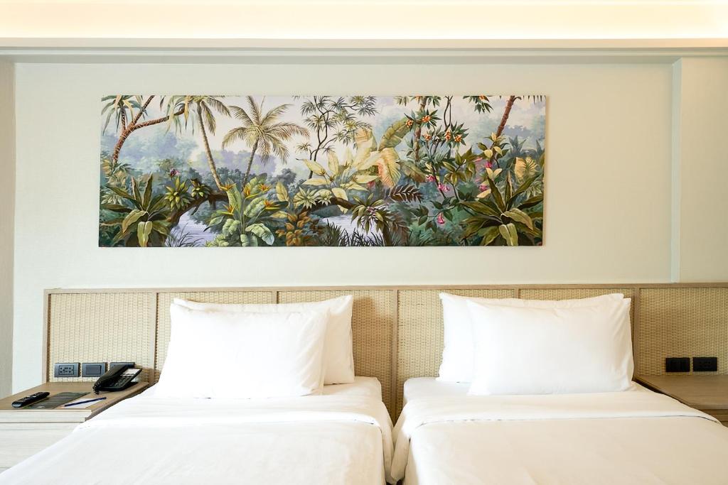 Mūsdienu viesnīcas numurs ar divām gultām un tropisku ainavu gleznu virs gultām, radot relaksējošu atmosfēru.