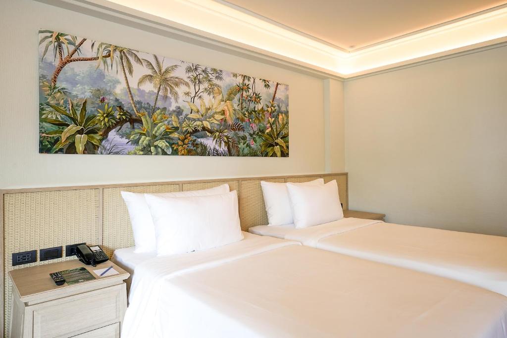 Kopmītne ar divām gultām un tropu ainavu gleznu virs galvas. Telpa ir gaiša un moderni iekārtota, ar koka mēbelēm un minimālu dekoru.