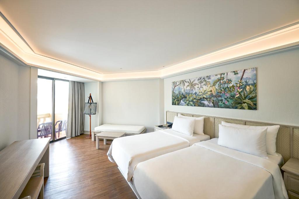 Mūsdienīgs viesnīcas numurs ar divām gultām, gaišu interjeru un augu motīvu gleznu uz sienas. Numurā ir liels logs, kas nodrošina dabiski apgaismotu telpu.