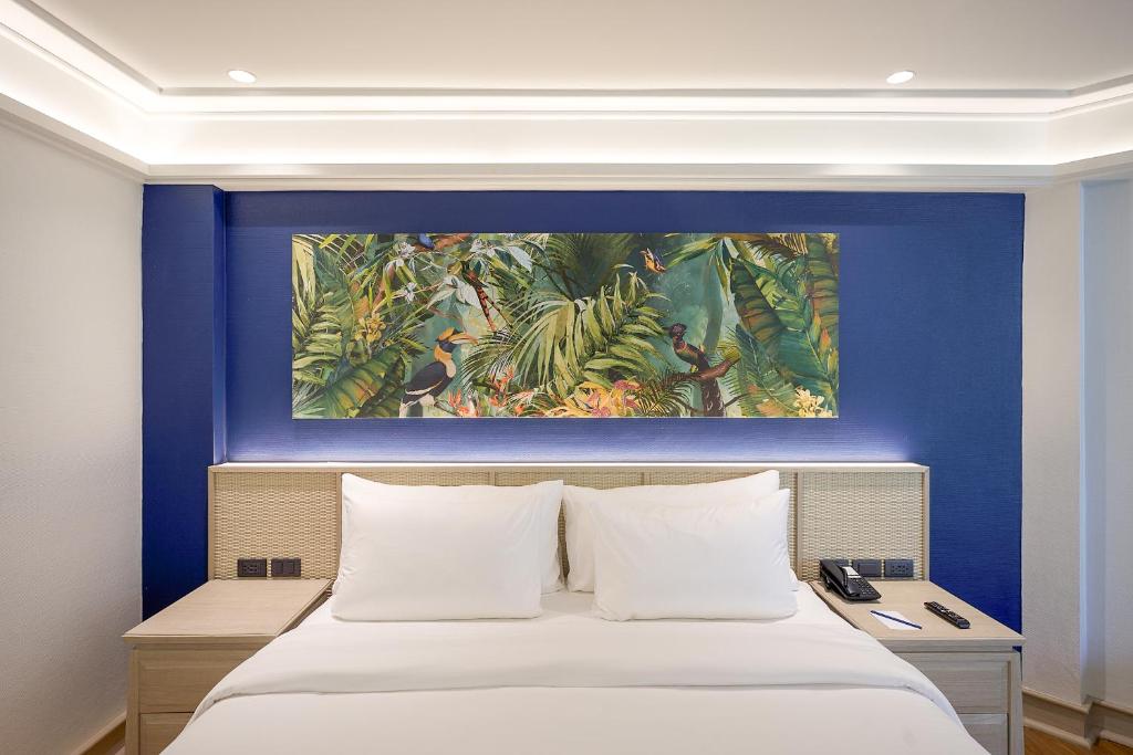 Mūsdienīgs guļamistabas interjers ar tropu augu attēlu uz sienas un ērtu gultu. Ideāla atmosfēra relaksācijai un atpūtai.