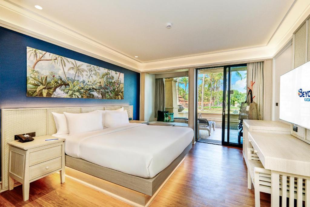 Mūsdienīga viesnīcas istaba ar plašu gultu, stilīgu interjeru un izkārtojumu, kas ietver terasi ar skatu uz dārzu. Glezna ar tropu ainavu papildina istabas atmosfēru.