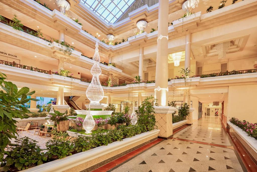 Luksusa viesnīcas interjers ar plašu, gaišu halli, kurā ir daudzas augplants un moderna apgaismojuma sistēma. Eleganci piešķir arhitektoniskie elementi un atpūtas zonas.