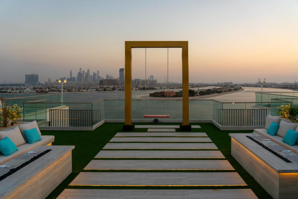 Mūsdienīgs jumta terases dizains ar šūpoļu rāmi un skatu uz pilsētu, kas ir apņemta ar ūdeni un apgaismojumu. Ideāla vieta relaksācijai un atpūtai.