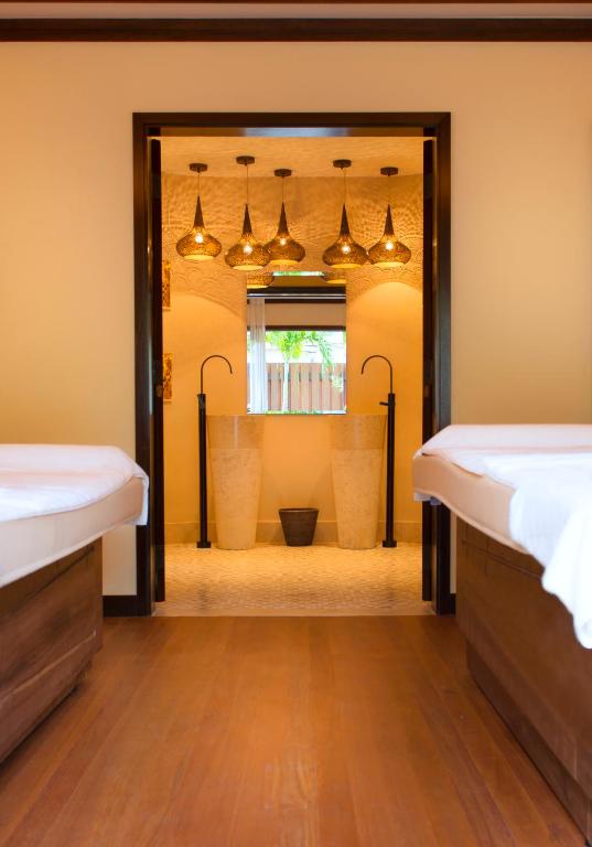 Mūsdienīga spa telpa ar elegantām gaismas ķermeņiem un diviem izsmalcinātiem izlietnēm, kas rada relaksējošu atmosfēru. Koka grīda un siltas krāsas sienas piešķir mājīgumu.