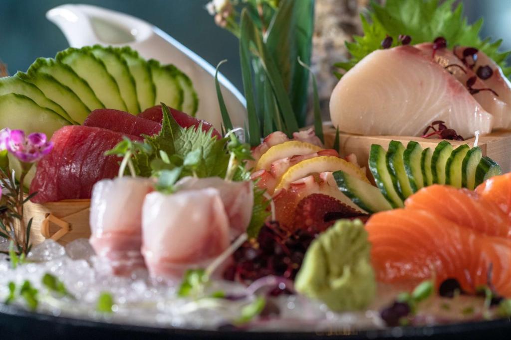 Svaigi sagatavots sushi un sashimi izvēlne ar dažādām zivīm, dārzeņiem un aromātiskām garšvielām, pasniegta uz ledus.