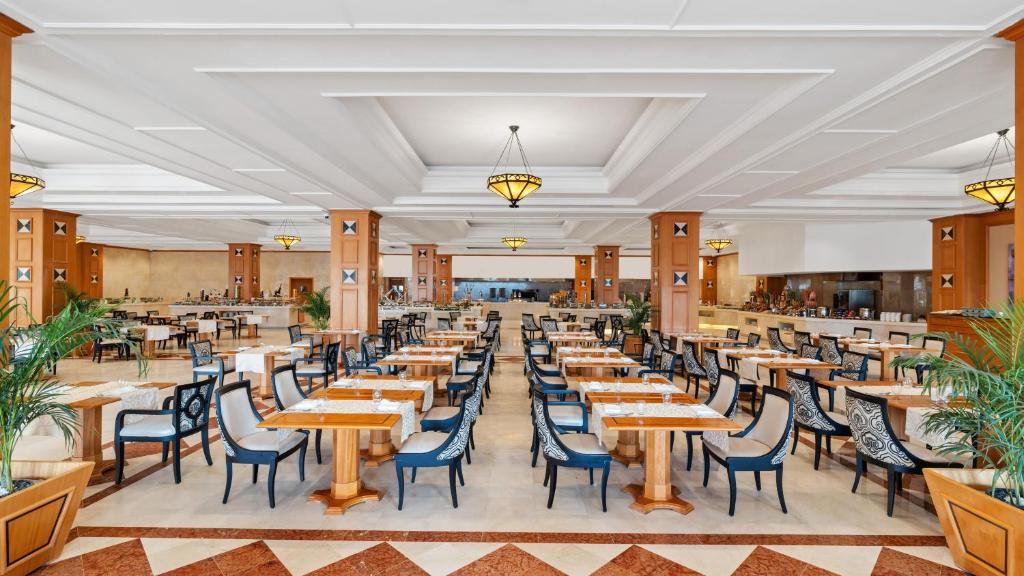 Mūsdienīgs restorāns ar plašu telpu, kurā ir eleganti galdi un krēsli, kā arī dekoratīvas augu kompozīcijas. Gaismas ķermeņi piešķir siltu atmosfēru.