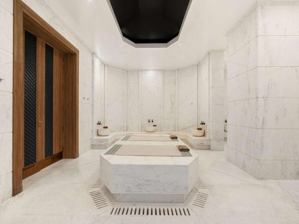 Mūsdienīga marmora pirts ar elegantām detaļām un siltu koka durvju. Telpa ir plaša un gaiša, radot relaksējošu atmosfēru.