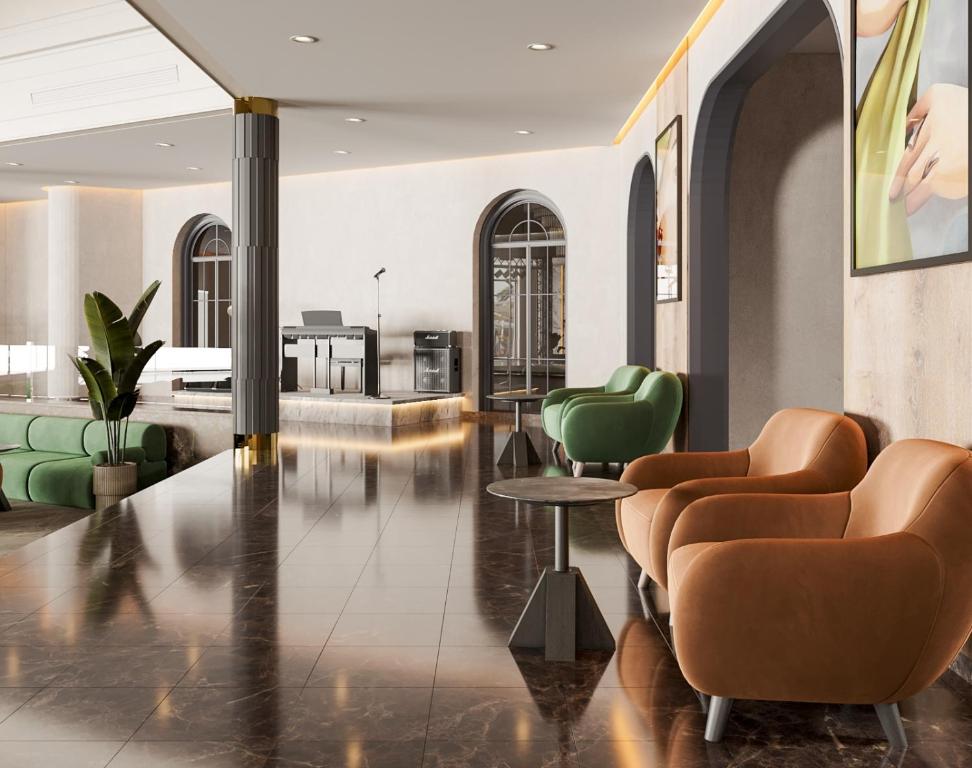 Mūsdienīga viesnīcas uzgaidāmā telpa ar stilīgām krēsliem un zaļiem dārza augiem, radot relaksējošu atmosfēru. Interjerā ir redzams elegants apgaismojums un moderns dizains.