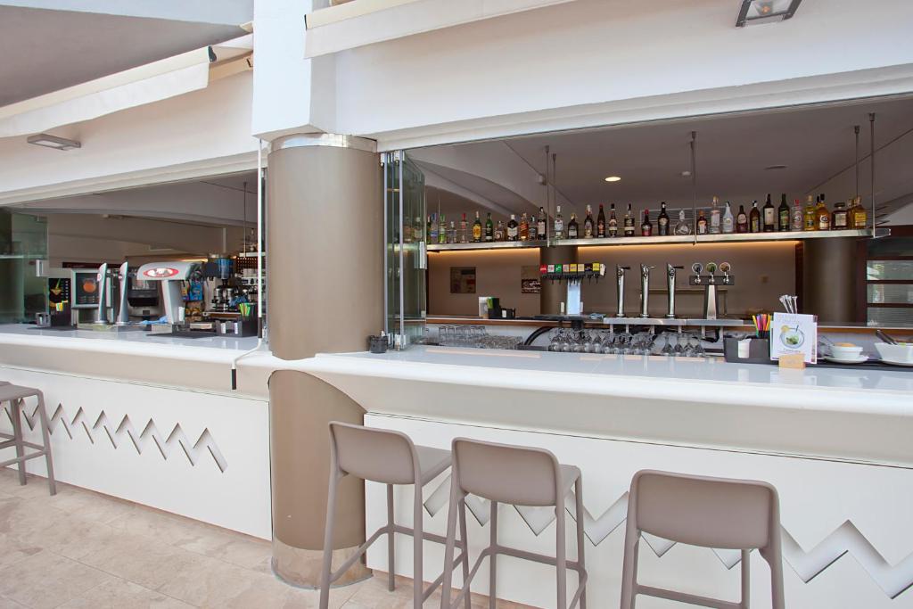 Mūsdienīgs bārs ar elegantu dizainu, kurā redzamas dzērienu izvēles un sēdvietas. Idealizēta atmosfēra relaksācijai un izklaidei.