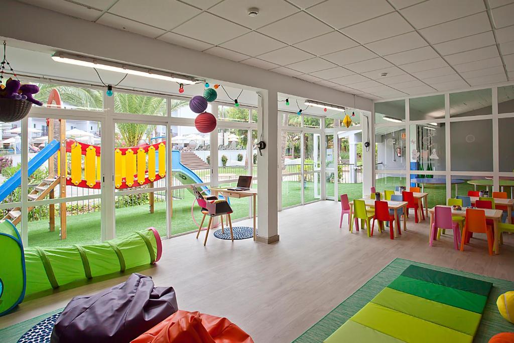 Krāsaina bērnu spēļu telpa ar rotaļu elementiem, piemēram, slidkalniņu un tuneli, kā arī dažādām krāsainām galdiem un krēsliem. Telpa ir gaiša un draudzīga, ar skatu uz ārējo dārzu.