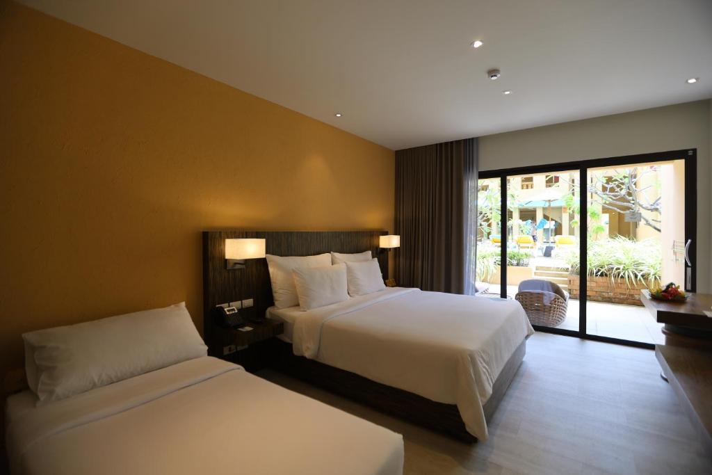 Mūsdienīgs viesnīcas numurs ar divām gultām un lieliem logiem, kas nodrošina skatu uz dārzu. Telpa ir elegantā dizainā ar siltām krāsām un ērtu apgaismojumu.