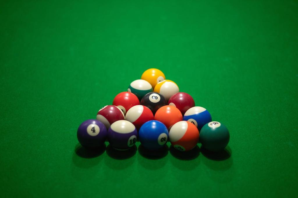 Bola komplekts, sakārtots triāna formā uz zaļā biljarda galda, iekļaujot dažādu krāsu un numuru bumbas.
