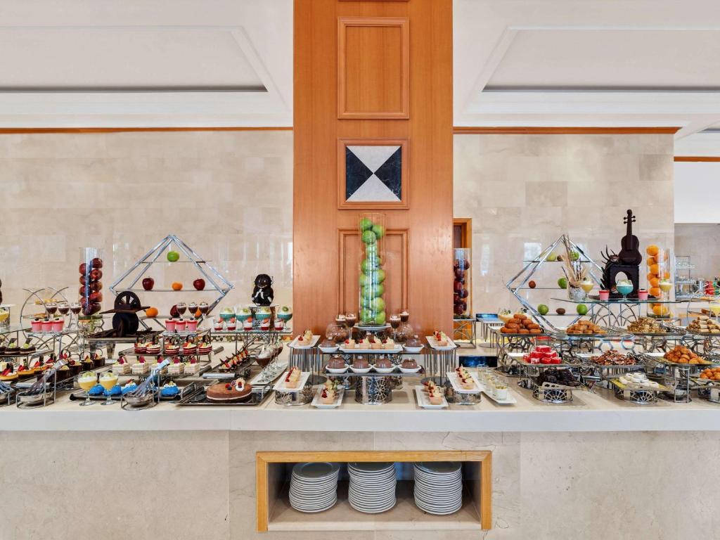 Bagātīgs desertu bufete ar dažādām kūkām, augļiem un saldumiem, kas sakārtoti eleganti uz galda. Ideāla vieta saldumu mīļotājiem.