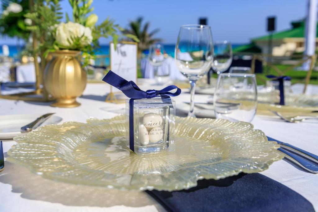 Elegants galda iestatījums ar ziediem un personalizētu dāvaniņu, kas dekorēts ar zilu lentu, pie jūras. Skaista atmosfēra svinībām.