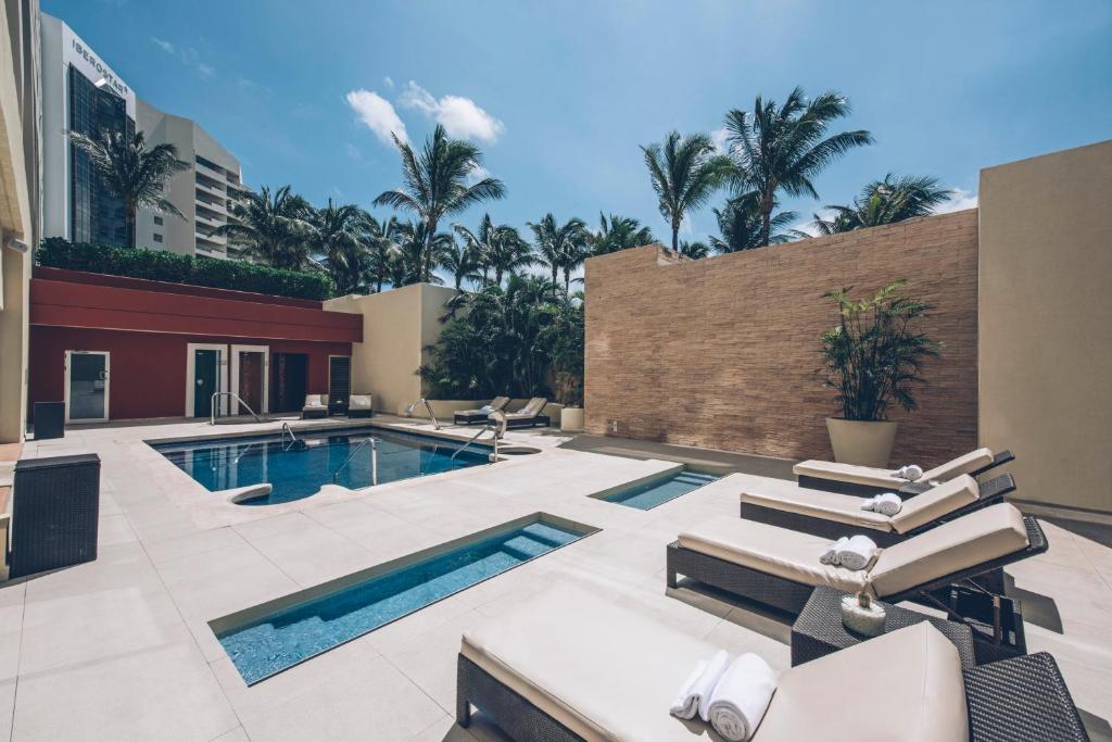 Mūsdienīga atpūtas zona ar peldbaseinu, sauļošanās krēsliem un palmām, kas nodrošina relaksējošu atmosfēru. Ideāla vieta atpūtai un izklaidei.