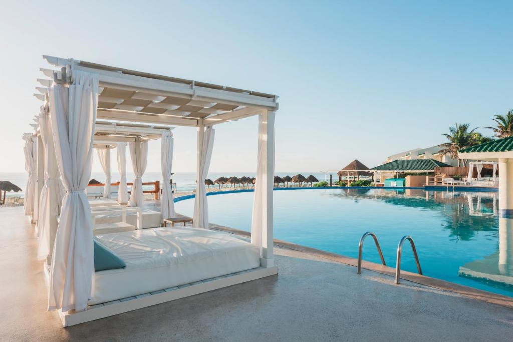 Luksusa atpūtas vieta ar baseinu, baltiem gultām un palmām, kas atrodas blakus pludmalei. Ideāla vieta relaksācijai un atpūtai saulainā laikā.