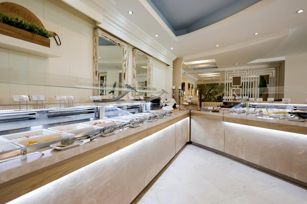 Mūsdienīgs bufetes galds ar elegantu dizainu, kas piedāvā dažādas ēdienu izvēles, ieskaitot uzkodas un salātus. Gaisma akcentē interjera detaļas un rada patīkamu atmosfēru.