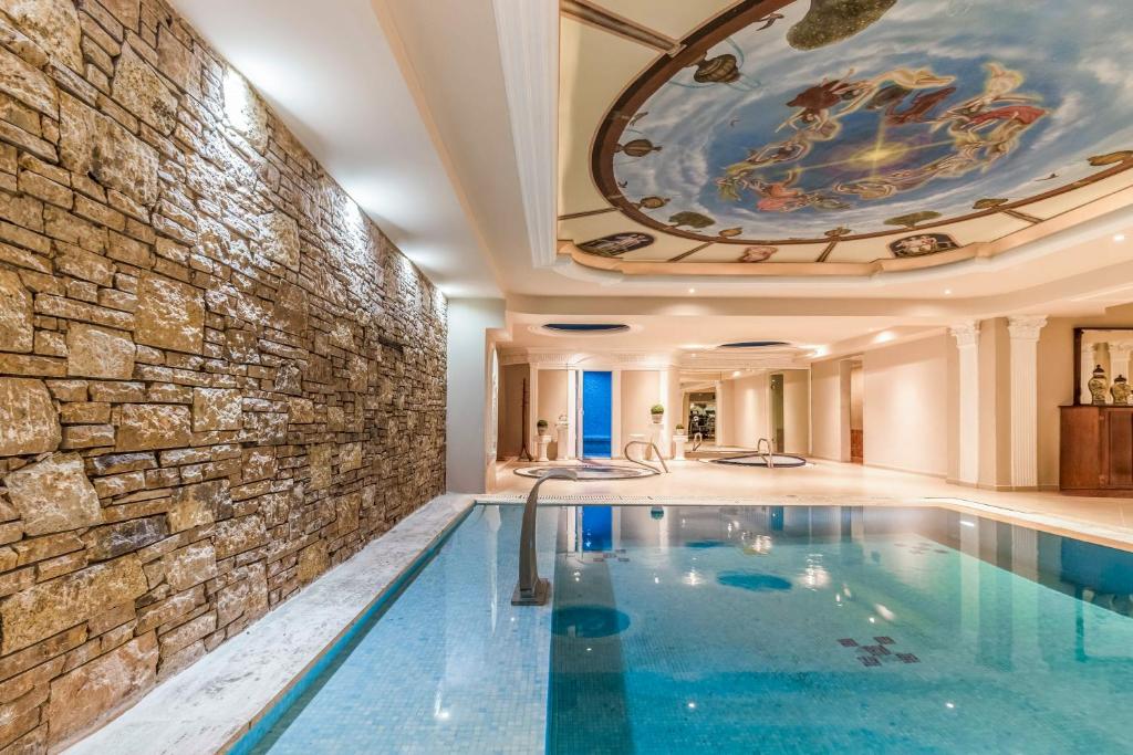 Luksusa iekštelpu spa ar baseinu un dekoratīvu griestu gleznojumu, kas rada relaksējošu atmosfēru. Akmens siena piešķir siltumu un eleganci šai telpai.