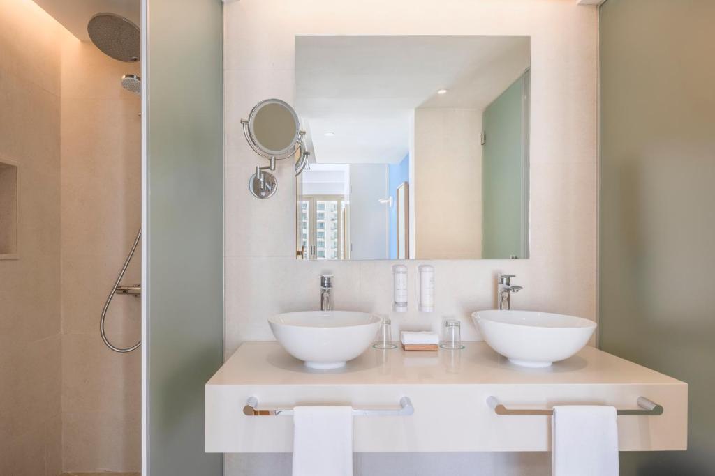 Mūsdienīgs vannas istabas interjers ar divām izlietnēm un spoguli. Svaiga un tīra atmosfēra ar minimālistisku dizainu.